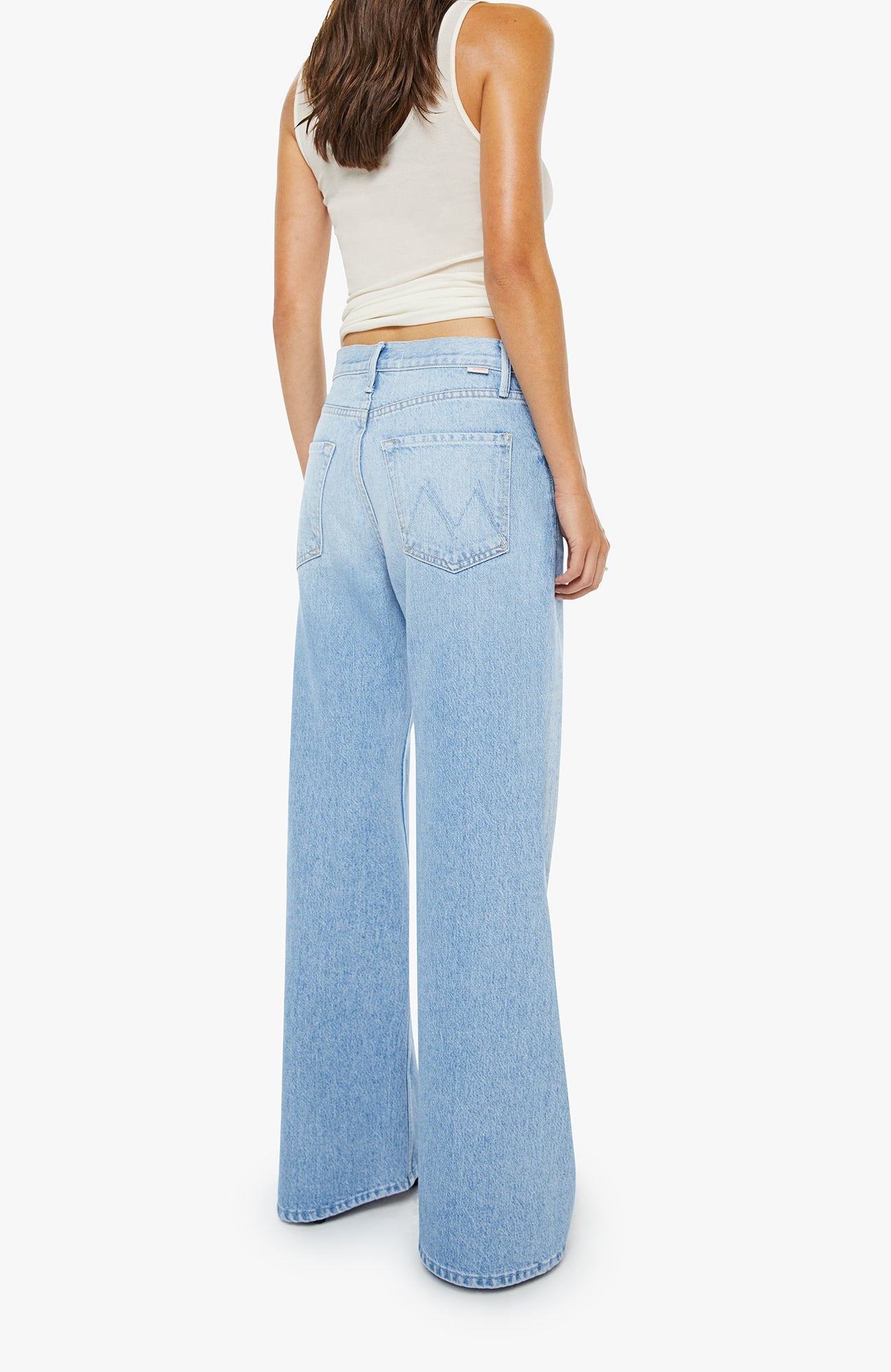 Person wearing light blue wide-leg jeans and a white top on a white background