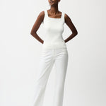 Woman wearing a white sleeveless top and pants on a white background