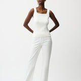 Woman wearing a white sleeveless top and pants on a white background