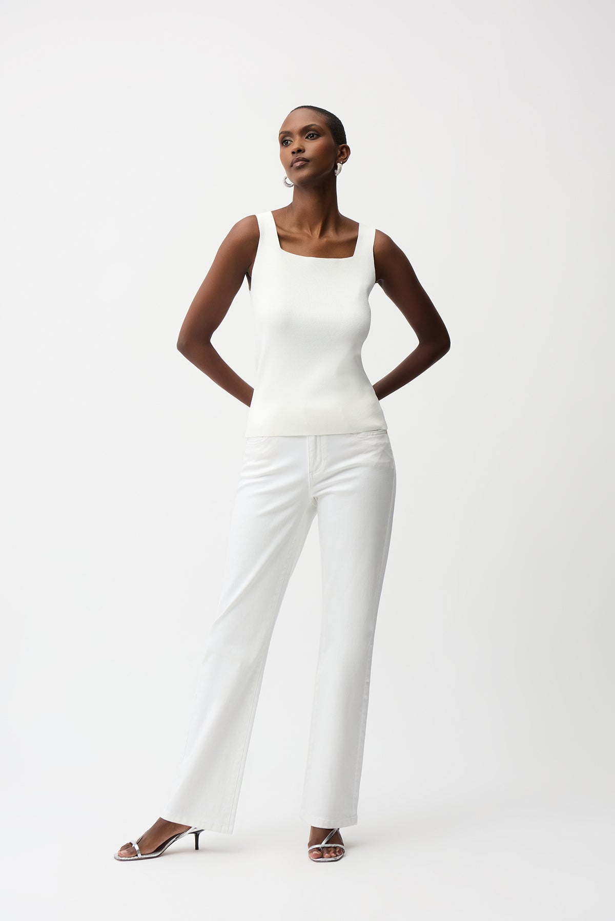 Woman wearing a white sleeveless top and pants on a white background