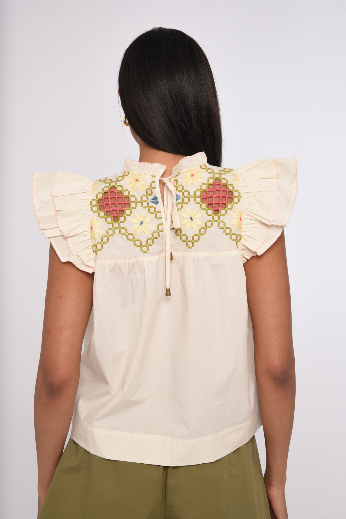Model wearing an ivory sleeveless blouse with a relaxed fit.