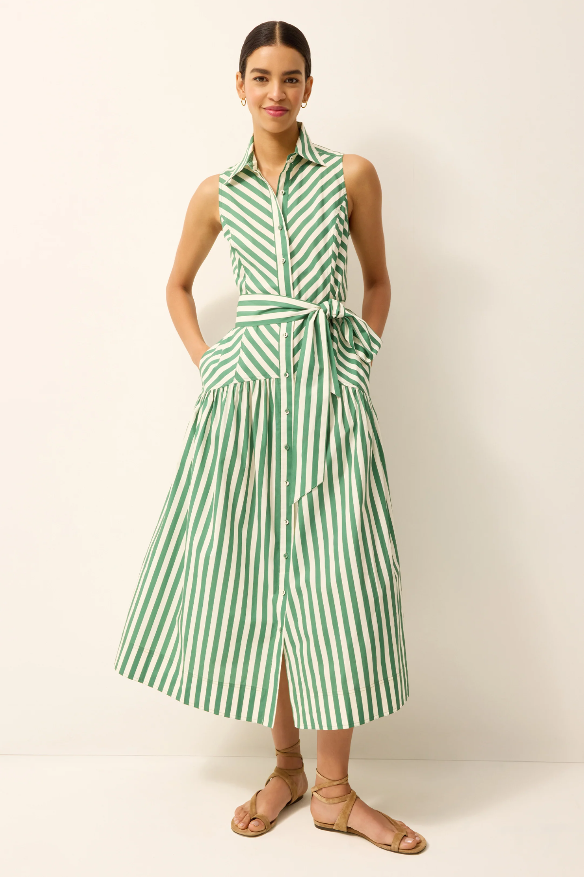 Woman wearing a green and white striped dress against a plain background