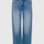 Light blue denim jeans with decorative gold-tone rivet detailing running down the outer seams, shown against a light gray background.
