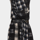 A sleeveless high-neck plaid dress with a wrap-style draped bodice and a matching pleated skirt, featuring a self-tie belt with a gold buckle. The dress has a black, white, and gray plaid pattern.