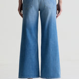 Blue wide-leg jeans worn by a person on a light gray background