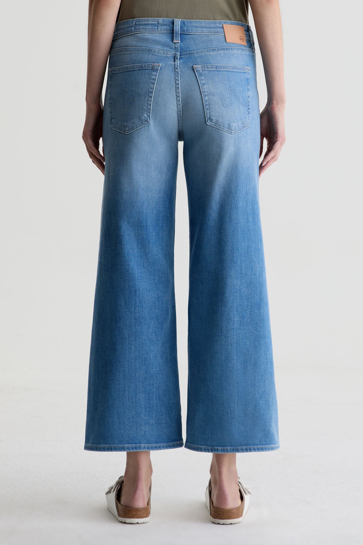 Blue wide-leg jeans worn by a person on a light gray background