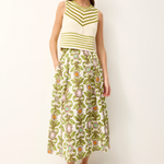 Woman wearing a green and white striped sleeveless top with a floral skirt on a white background