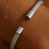 Silver textured bracelet on a person's wrist against a brown background
