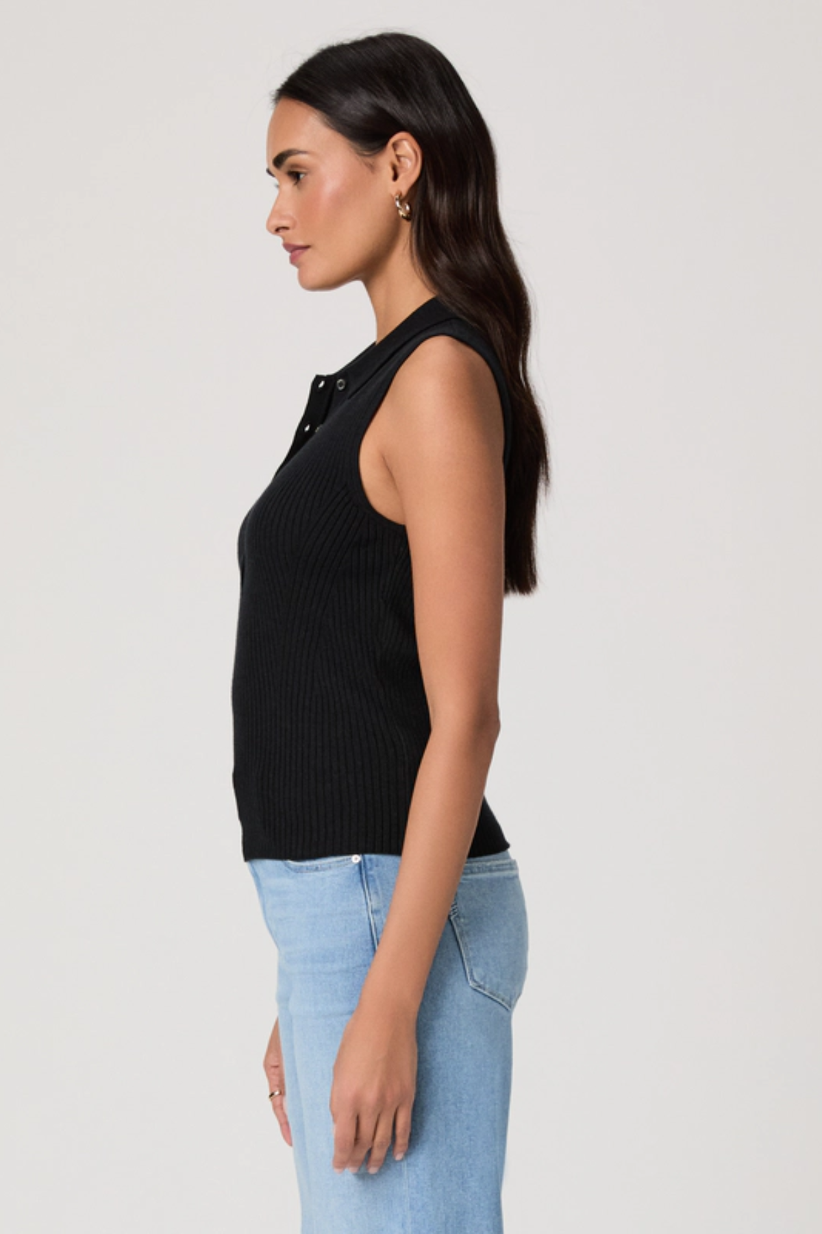 side view of person in black top and denim on white background 