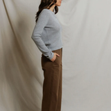 side of woman in grey cardigan and brown pants 