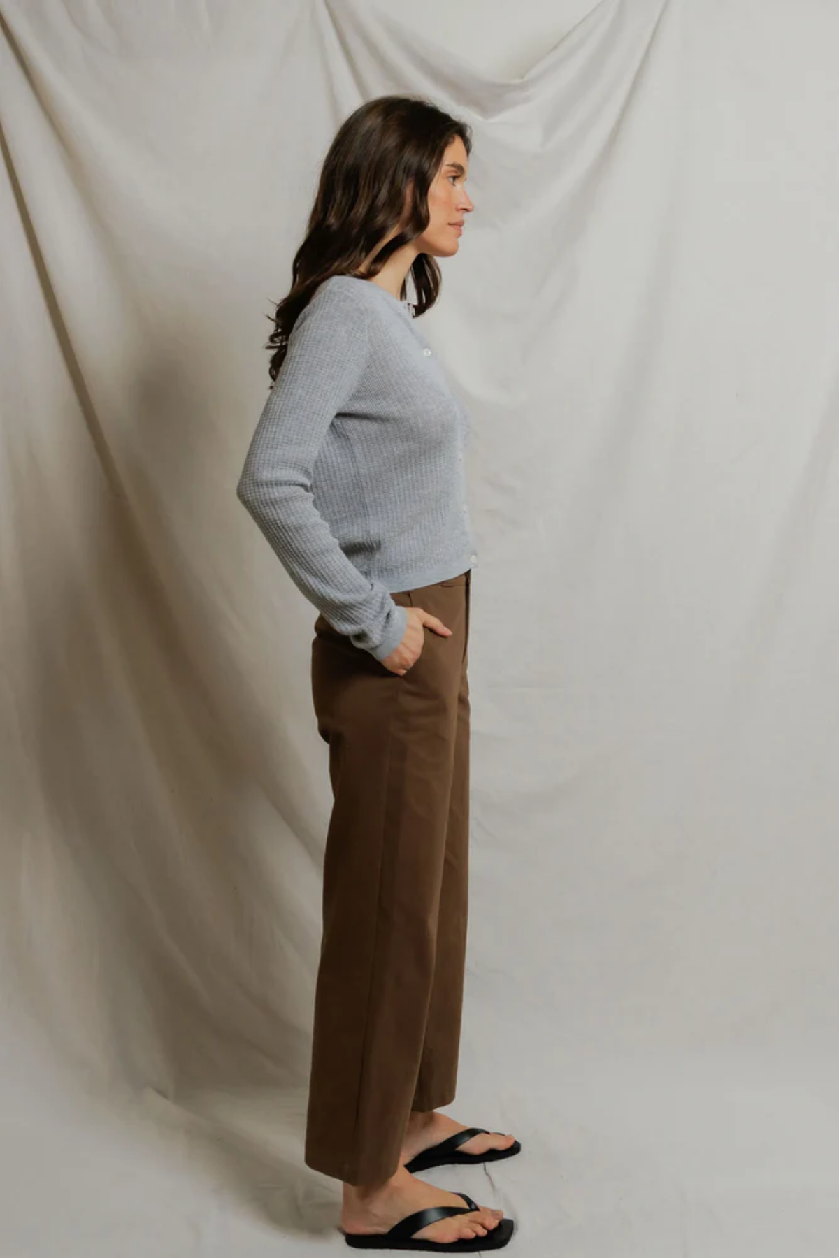 side of woman in grey cardigan and brown pants 