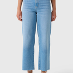 A model wearing light blue cropped jeans with a straight-leg fit, paired with a patterned top and beige sandals, shown from the waist down on a light gray background.
