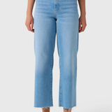 A model wearing light blue cropped jeans with a straight-leg fit, paired with a patterned top and beige sandals, shown from the waist down on a light gray background.