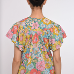 Person wearing a colorful floral blouse on a white background