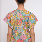 Person wearing a colorful floral blouse on a white background