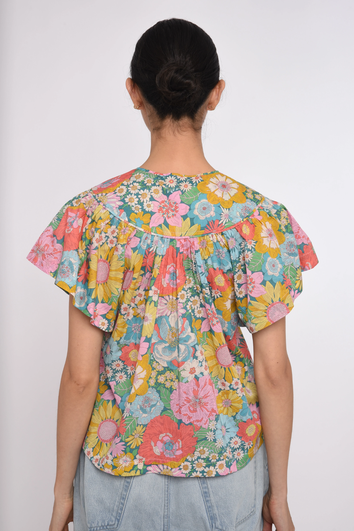 Person wearing a colorful floral blouse on a white background