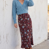 Model wearing floral skirt and blue top on a white background