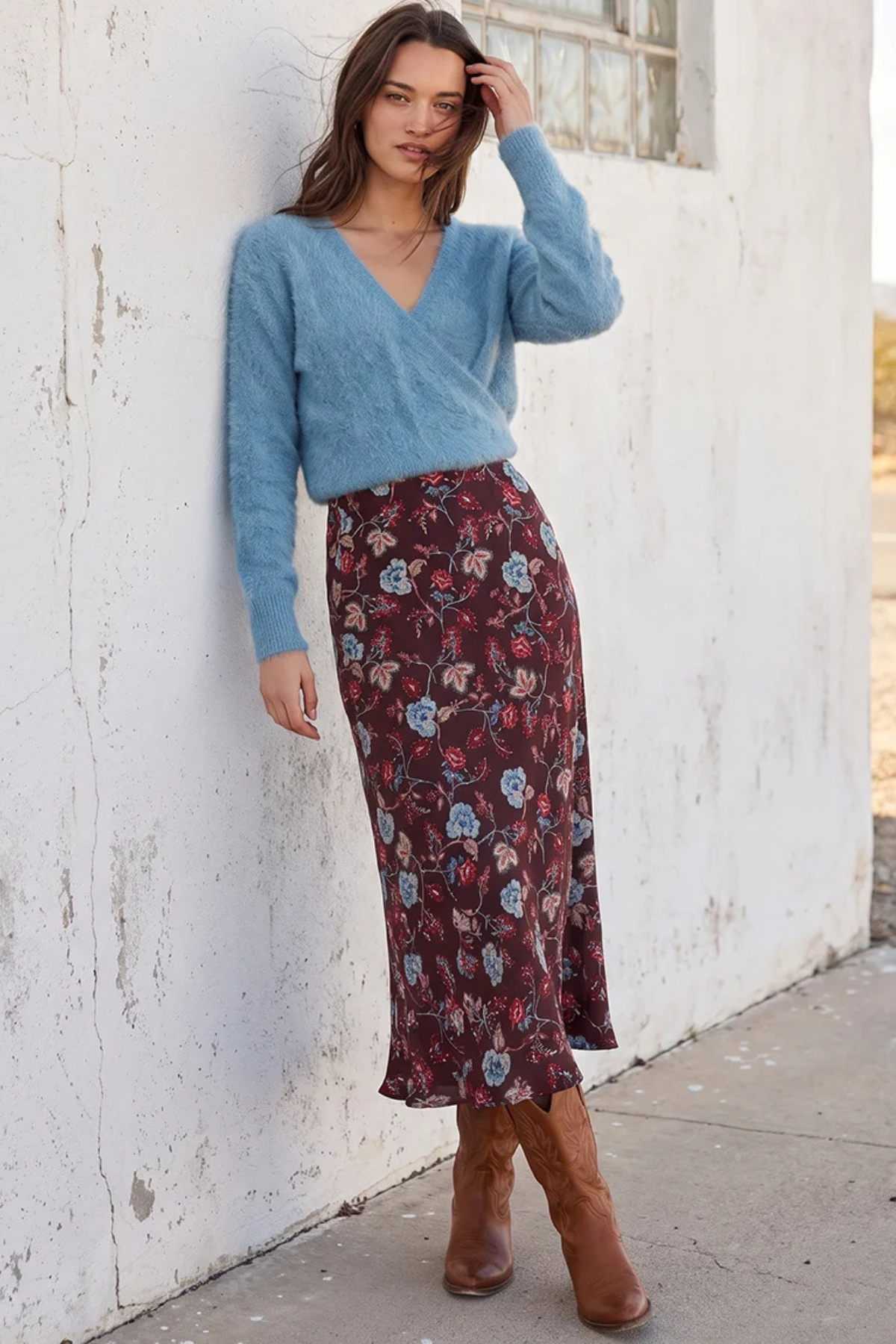Model wearing floral skirt and blue top on a white background