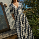 Woman wearing a black and white striped dress standing outdoors.