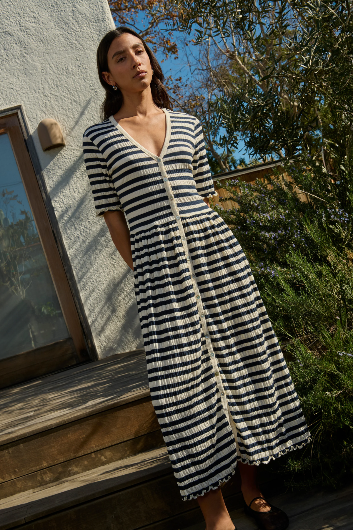 Woman wearing a black and white striped dress standing outdoors.