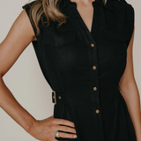 Model wearing a sleeveless black midi dress with a tailored silhouette and subtle front detailing, photographed against a neutral studio background.