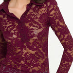 Woman wearing a burgundy lace long-sleeve top with a blurred background