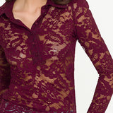 Woman wearing a burgundy lace long-sleeve top with a blurred background