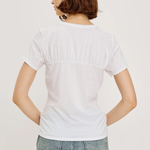 Person wearing a plain white t-shirt and jeans on a light background