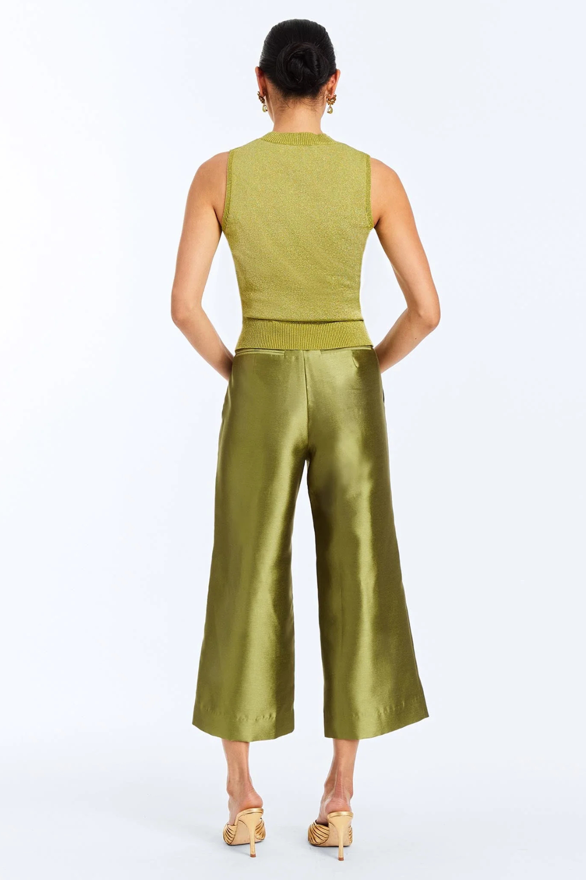 A woman shown from the back wearing a sleeveless olive green top and matching wide-leg cropped pants, paired with beige heels, against a plain white studio background.