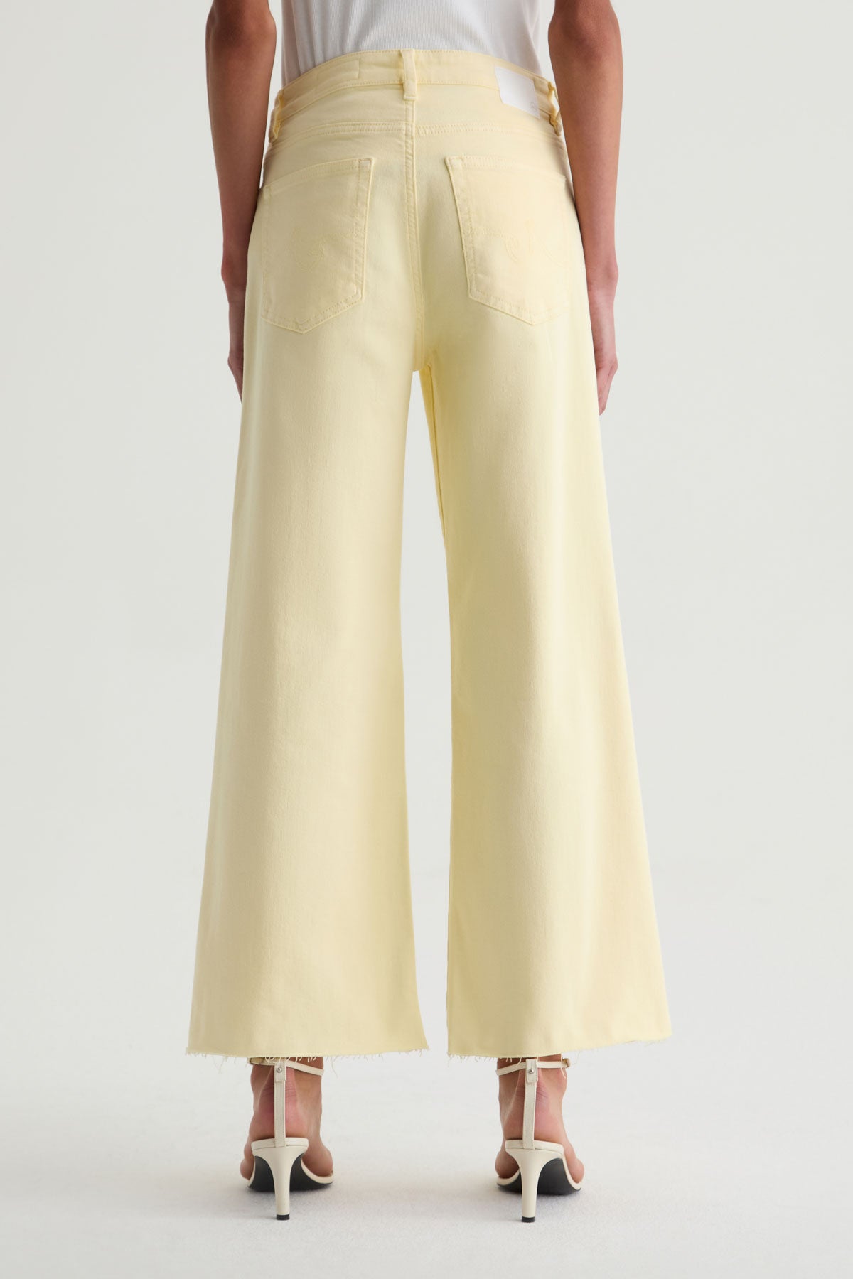 Light yellow wide-leg pants worn by a person on a white background
