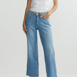 Person wearing a white tank top and blue jeans on a plain background