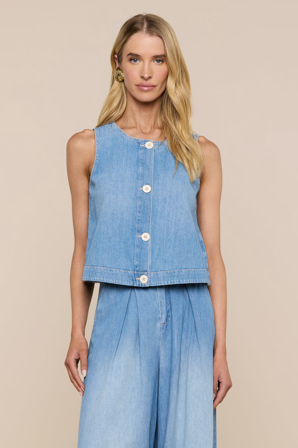Woman wearing a sleeveless denim top and long denim skirt on a beige background
