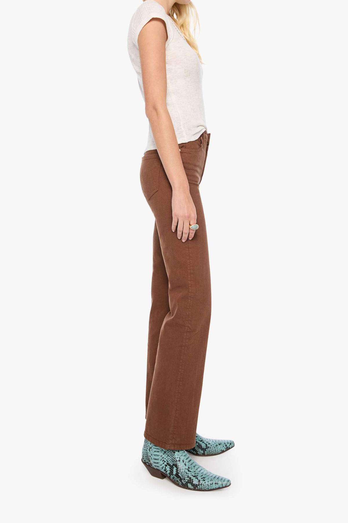 A side-profile view of a model wearing brown wide-leg pants, a white sleeveless top, and green snakeskin-patterned boots against a plain white background.