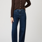 Woman wearing a brown ribbed sweater and blue jeans on a white background