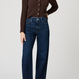 Woman wearing a brown ribbed sweater and blue jeans on a white background
