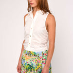Woman wearing a white sleeveless blouse and colorful floral skirt on a white background