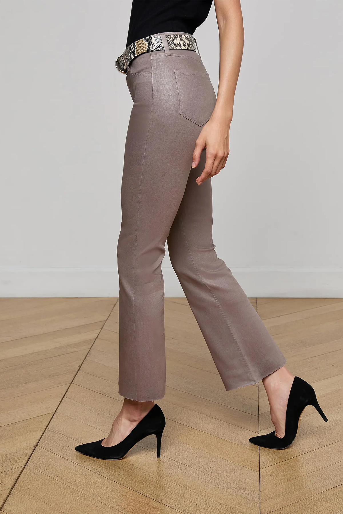 Person wearing beige pants and black high-heeled shoes on a wooden floor.