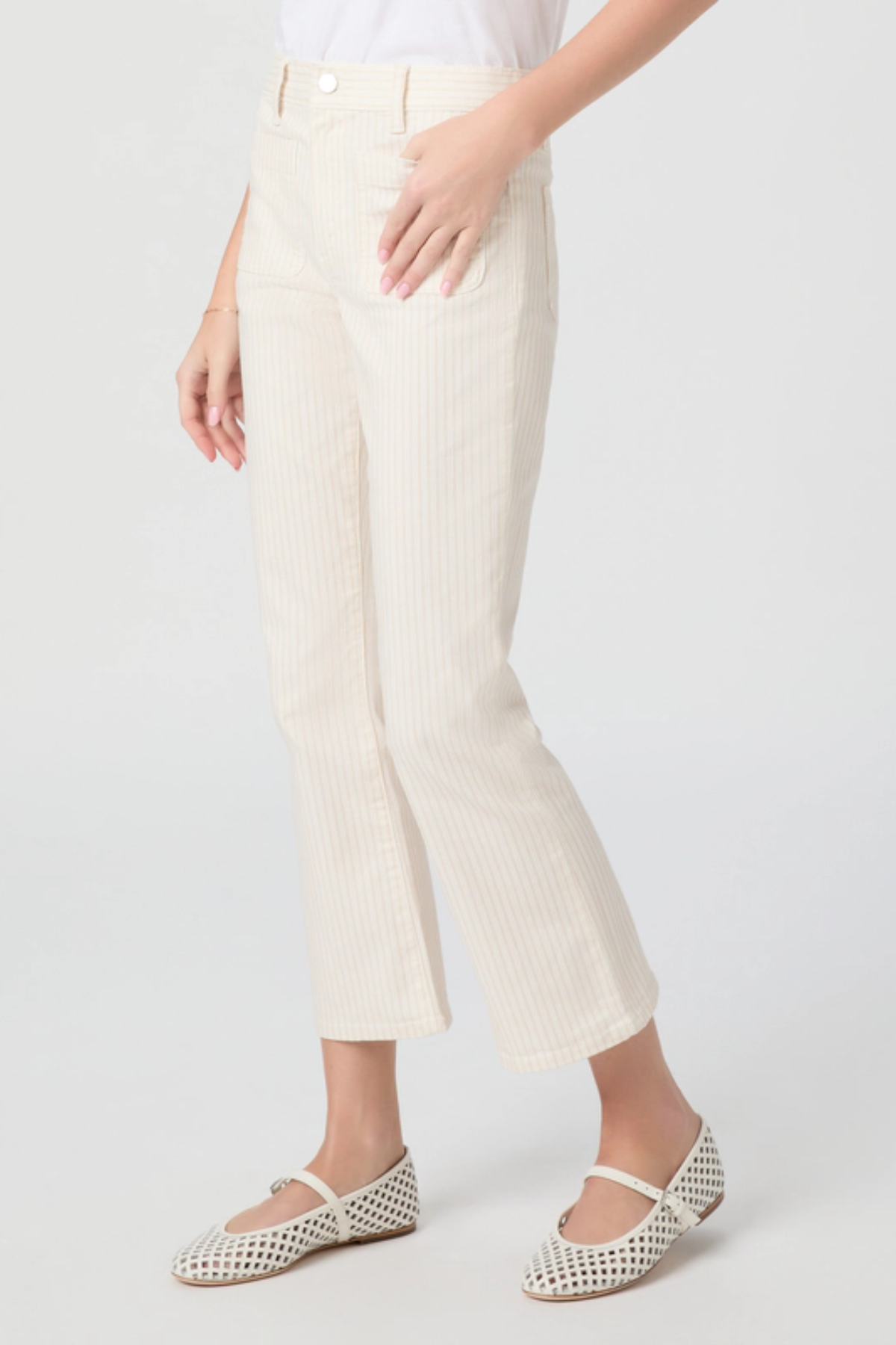 Person wearing white pants and white flats on a light gray background