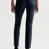 Rear view of a model wearing dark navy blue slim-fit jeans and black ankle boots against a light gray studio background.