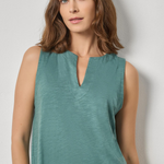 Woman wearing a teal sleeveless top against a plain background