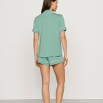 Woman wearing a green pajama set on a plain background