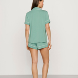 Woman wearing a green pajama set on a plain background