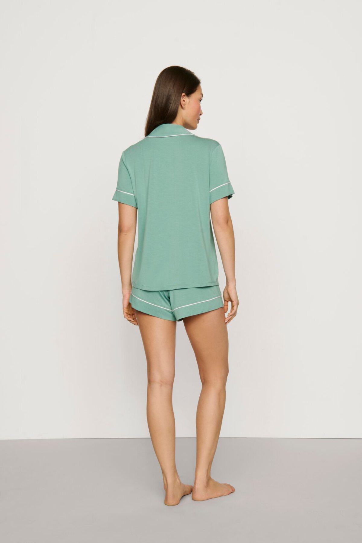 Woman wearing a green pajama set on a plain background