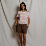 Woman wearing a striped shirt and brown shorts standing against a plain white background