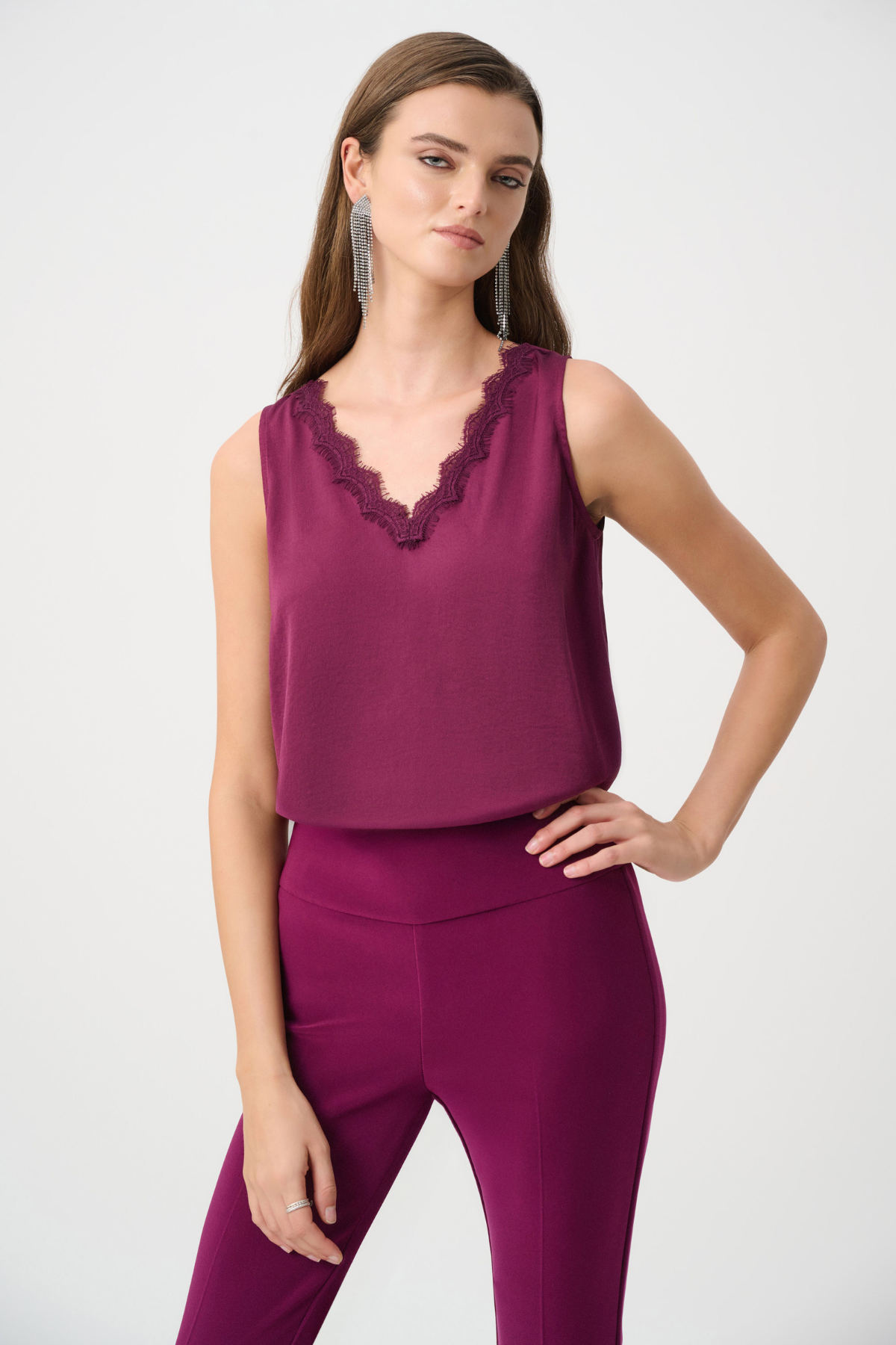 Woman wearing a sleeveless purple top with lace details and matching pants on a white background
