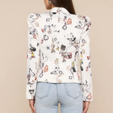 Woman wearing a white blouse with colorful geometric pattern and light blue jeans on a beige background