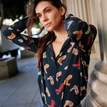 Woman wearing a patterned shirt and jeans standing outdoors.