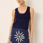 Woman wearing a navy blue sleeveless top and skirt with a floral pattern on a beige background