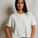 Woman wearing a white shirt and blue jeans against a plain background