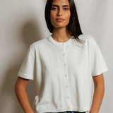 Woman wearing a white shirt and blue jeans against a plain background